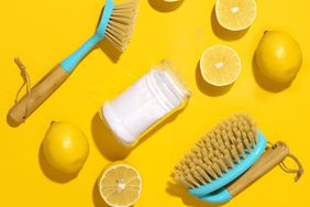 cleaning with lemons. Baking soda, lemon, and bamboo brushes against household chemicals products over yellow background. Effective and safe house cleaning