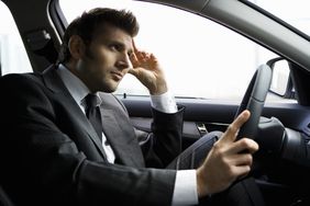 Stressed man wearing suit driving a car