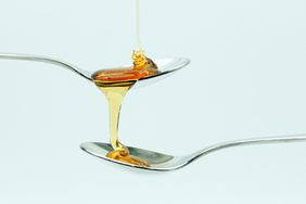 Honey Pouring On Spoon Over White Background